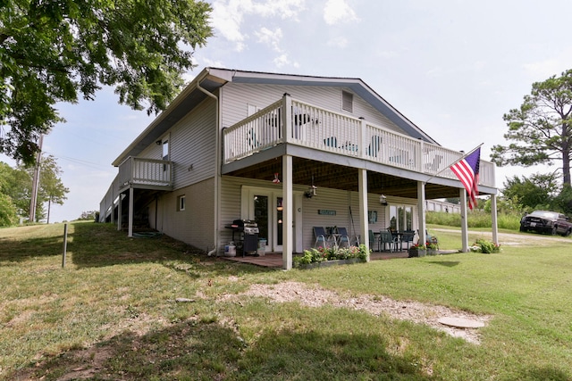 back of house with a wooden deck, a patio area, and a lawn