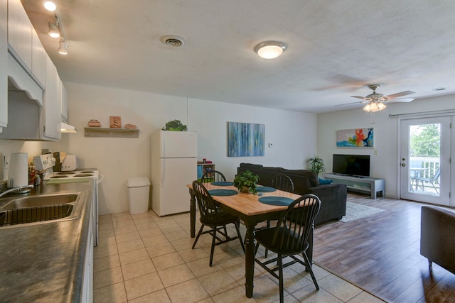 dining room featuring light hardwood / wood-style flooring, a textured ceiling, sink, and ceiling fan