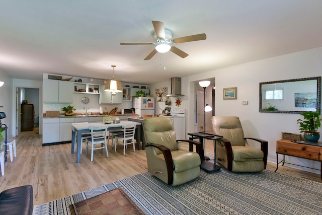 living room with sink, light hardwood / wood-style floors, and ceiling fan