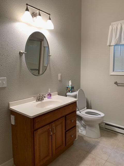 bathroom with baseboard heating, tile patterned floors, vanity, and toilet