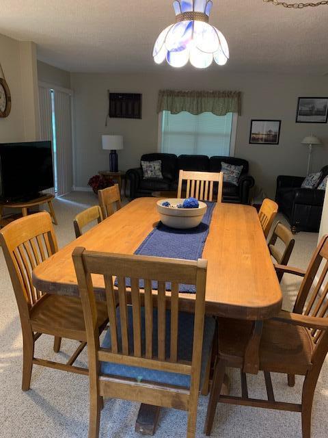 carpeted dining area with a textured ceiling