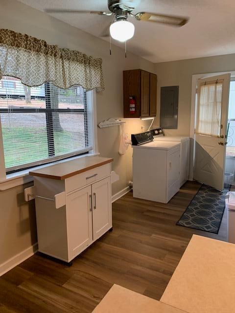 laundry area with electric panel, washing machine and clothes dryer, dark hardwood / wood-style floors, and cabinets