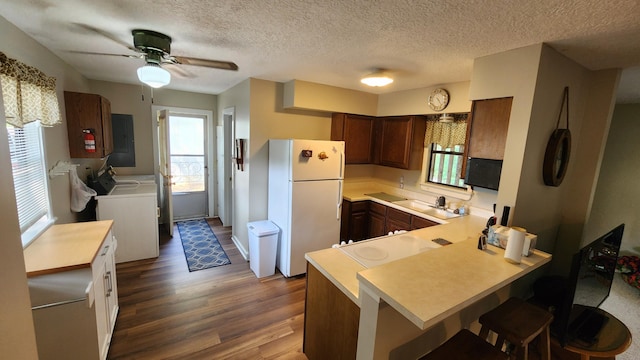 kitchen with washing machine and clothes dryer, a kitchen breakfast bar, dark wood-type flooring, kitchen peninsula, and white fridge