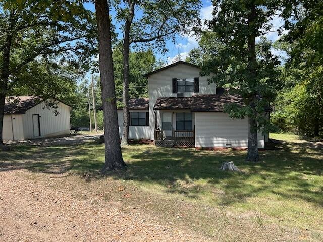 rear view of property with a storage shed and a yard