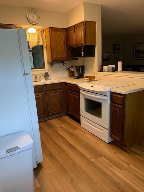 kitchen with light hardwood / wood-style flooring and white appliances