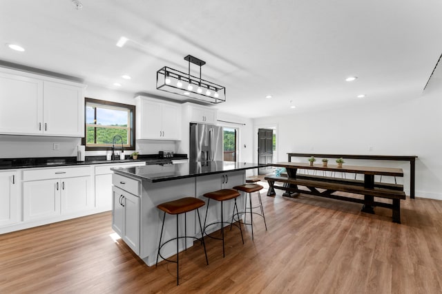 kitchen featuring a kitchen island, plenty of natural light, hanging light fixtures, and stainless steel refrigerator with ice dispenser