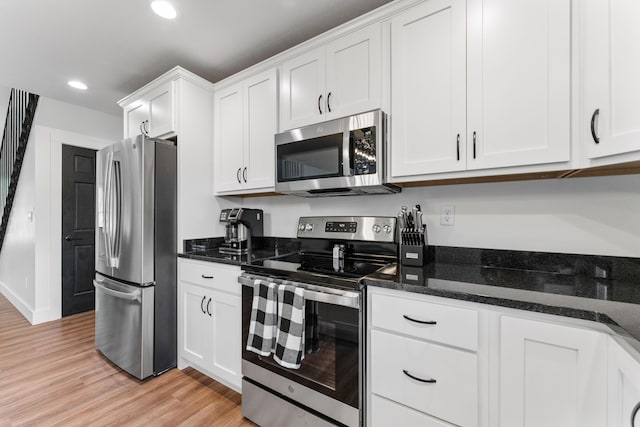 kitchen featuring dark stone counters, light hardwood / wood-style flooring, stainless steel appliances, and white cabinets