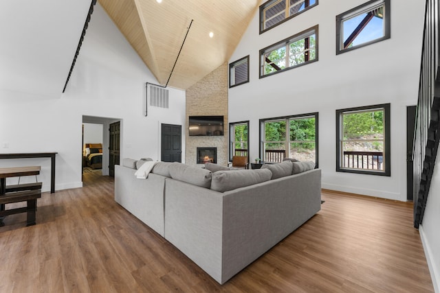 living room with wooden ceiling, a fireplace, a high ceiling, and hardwood / wood-style flooring