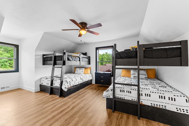 bedroom with ceiling fan, wood-type flooring, and multiple windows