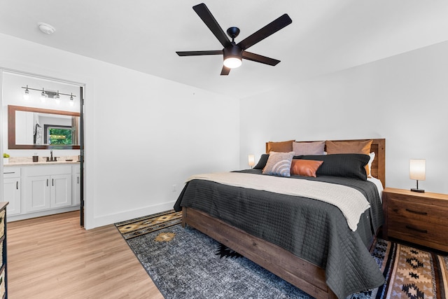 bedroom featuring ensuite bathroom, sink, light hardwood / wood-style flooring, and ceiling fan