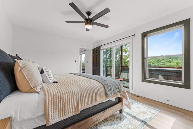 bedroom featuring access to exterior, multiple windows, ceiling fan, and light hardwood / wood-style floors