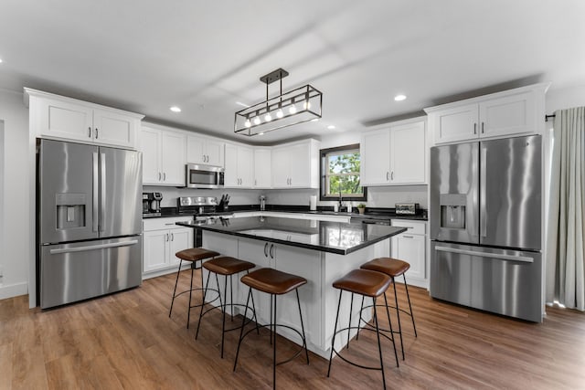 kitchen featuring hanging light fixtures, a kitchen island, dark wood-type flooring, white cabinetry, and stainless steel appliances