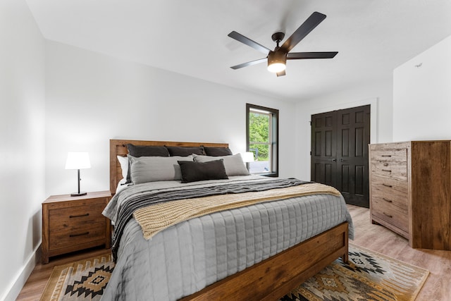 bedroom with a closet, light hardwood / wood-style floors, and ceiling fan