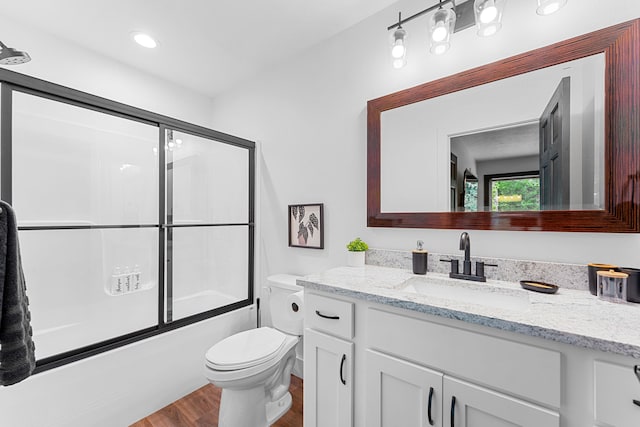 full bathroom featuring vanity, combined bath / shower with glass door, toilet, and hardwood / wood-style flooring