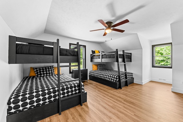 bedroom with ceiling fan, hardwood / wood-style flooring, lofted ceiling, and a textured ceiling