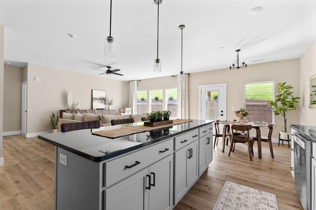 kitchen featuring a kitchen island, open floor plan, hanging light fixtures, a wealth of natural light, and dark countertops