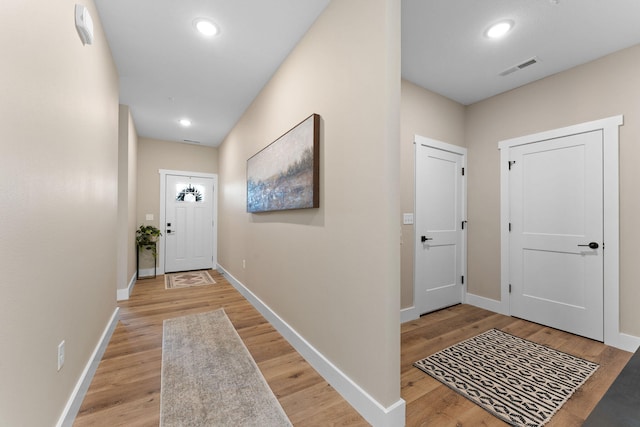 doorway to outside featuring baseboards, visible vents, and light wood finished floors