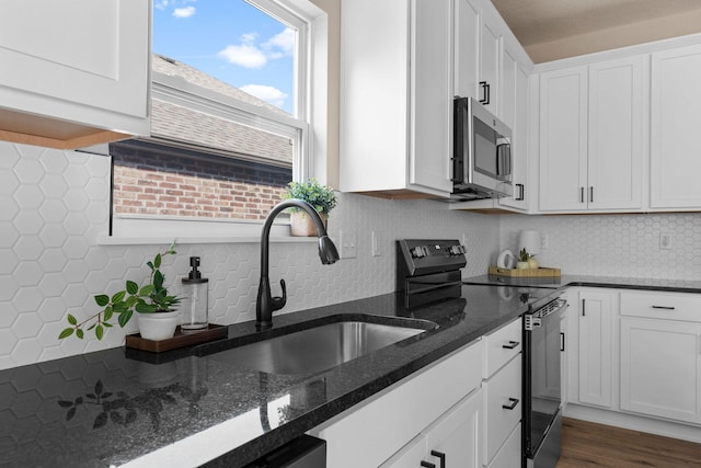 kitchen featuring black range with electric stovetop, white cabinetry, stainless steel microwave, and a sink