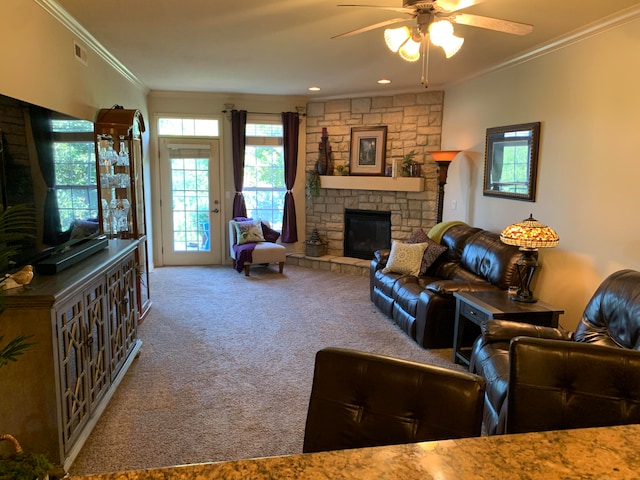 living room featuring ceiling fan, crown molding, carpet flooring, and a stone fireplace