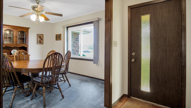 dining space with a ceiling fan, dark colored carpet, and baseboards