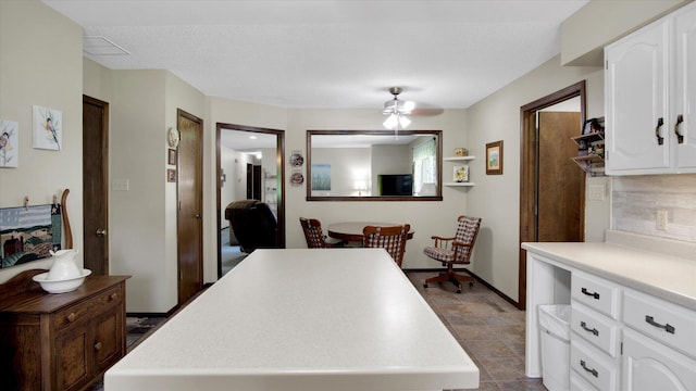 kitchen with white cabinets, decorative backsplash, a center island, light countertops, and fridge