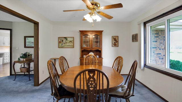 dining space with a ceiling fan, dark colored carpet, and baseboards