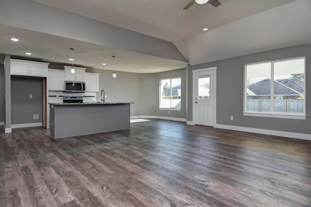 kitchen featuring white cabinetry, dark wood-type flooring, dark stone counters, and vaulted ceiling