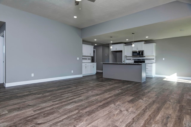 kitchen with white cabinets, dark wood-type flooring, appliances with stainless steel finishes, and a center island