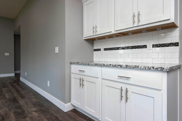 kitchen featuring white cabinets, light stone countertops, dark hardwood / wood-style floors, and backsplash