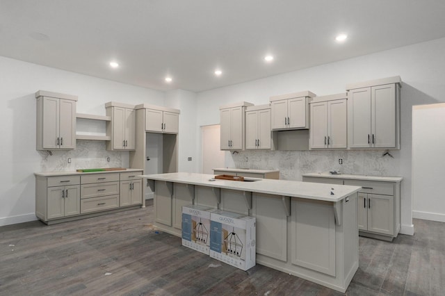 kitchen featuring backsplash, gray cabinets, dark hardwood / wood-style flooring, and a kitchen island