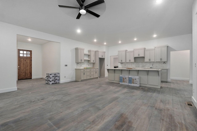 kitchen with tasteful backsplash, gray cabinetry, ceiling fan, light hardwood / wood-style flooring, and a center island