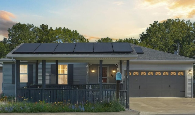 view of front facade featuring a garage, solar panels, and covered porch