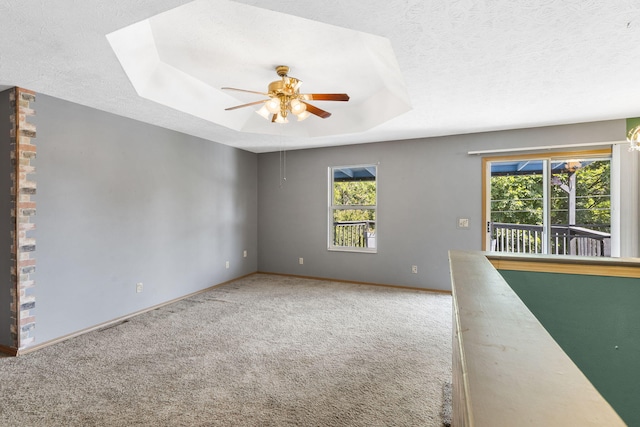 unfurnished room with a tray ceiling, carpet, a textured ceiling, and ceiling fan