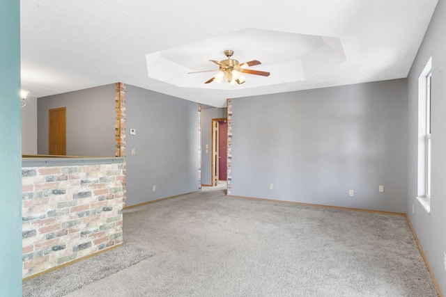 carpeted empty room featuring ceiling fan and a raised ceiling