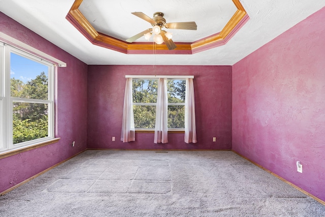 empty room featuring ceiling fan, light carpet, a raised ceiling, and crown molding