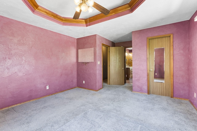 unfurnished bedroom featuring light colored carpet, a raised ceiling, ceiling fan, and crown molding