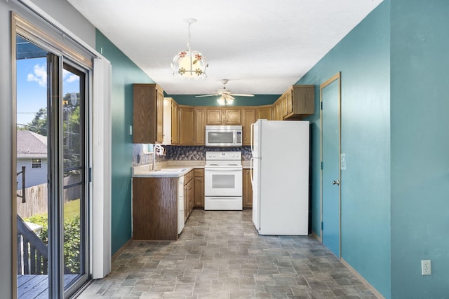 kitchen featuring hanging light fixtures, sink, ceiling fan, backsplash, and white appliances