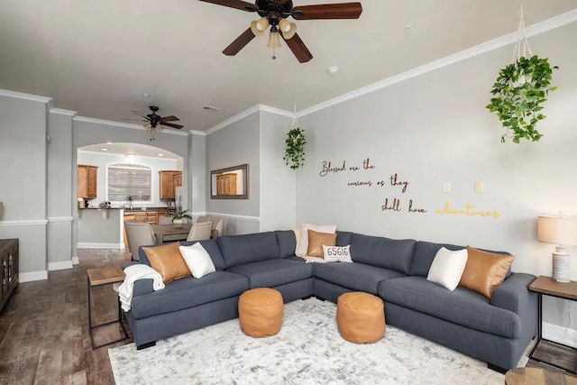 living room featuring dark wood-type flooring, ornamental molding, and ceiling fan