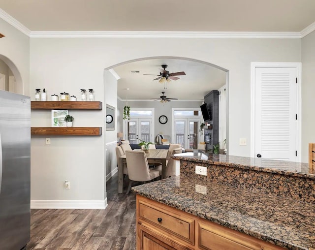 kitchen featuring stainless steel refrigerator, dark stone counters, crown molding, dark hardwood / wood-style flooring, and french doors