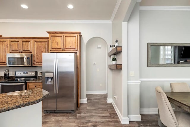 kitchen featuring appliances with stainless steel finishes, dark hardwood / wood-style floors, ornamental molding, and dark stone counters