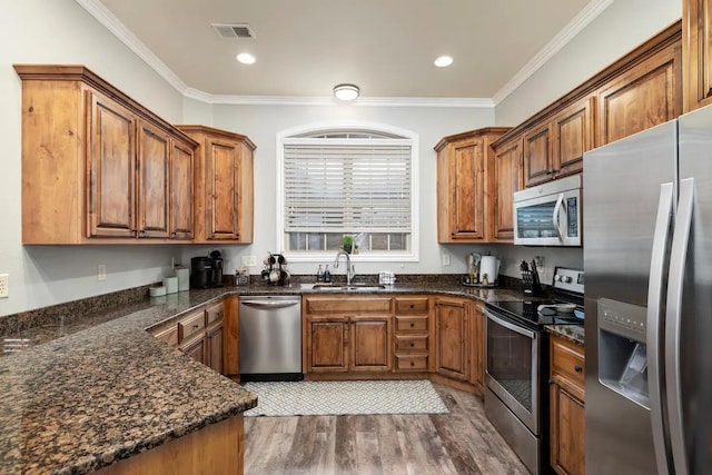 kitchen featuring dark hardwood / wood-style flooring, dark stone countertops, sink, ornamental molding, and appliances with stainless steel finishes