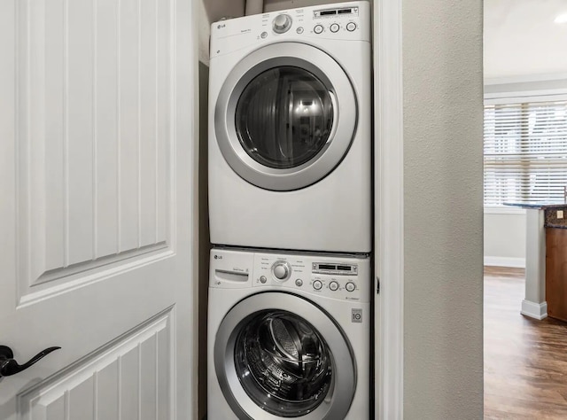 laundry room with wood-type flooring and stacked washer / dryer