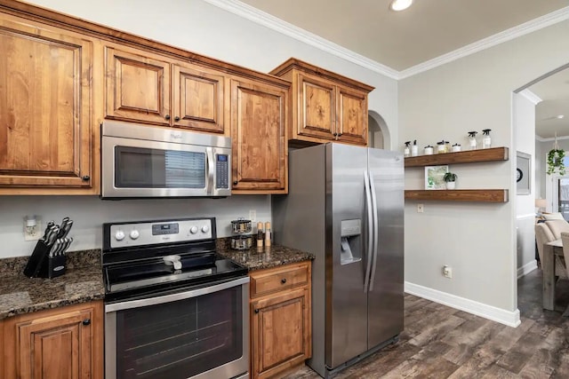 kitchen with dark stone counters, ornamental molding, appliances with stainless steel finishes, and dark hardwood / wood-style flooring