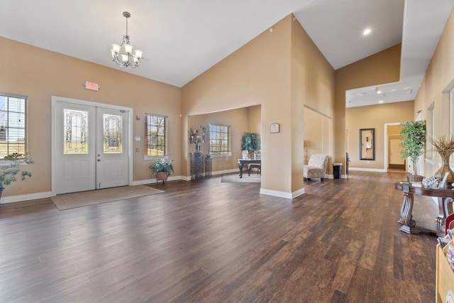 foyer with an inviting chandelier, high vaulted ceiling, and dark hardwood / wood-style flooring