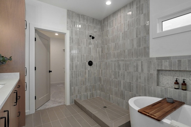 bathroom with shower with separate bathtub, tile patterned floors, vanity, and tile walls