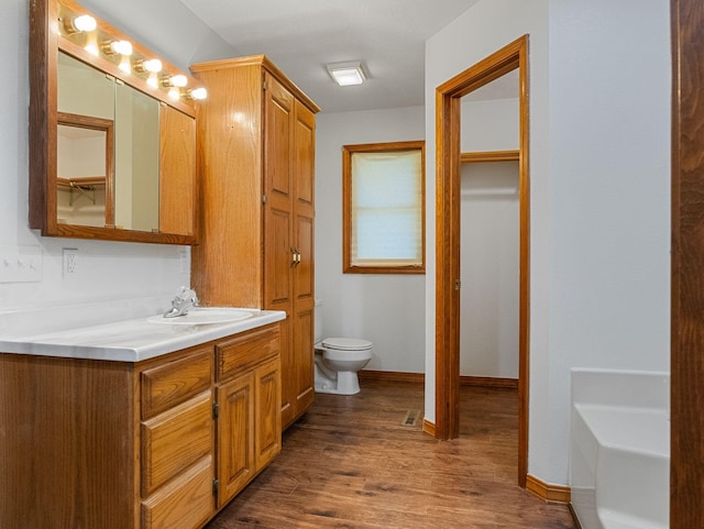 bathroom featuring vanity, hardwood / wood-style flooring, toilet, and a bath