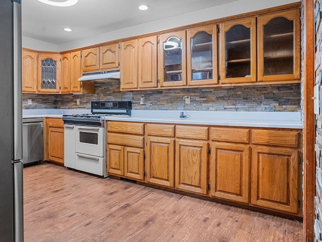 kitchen featuring dishwasher, backsplash, white range oven, and light hardwood / wood-style flooring