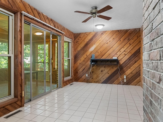 interior space featuring a textured ceiling, wooden walls, and ceiling fan