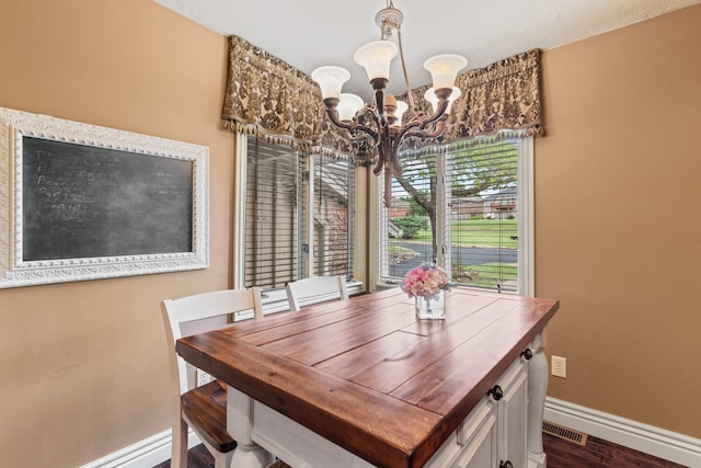 dining room with dark hardwood / wood-style floors and a chandelier