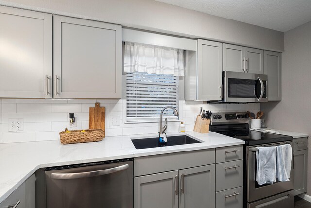 kitchen with stainless steel appliances, gray cabinets, and sink